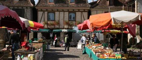 A traditional European market with stalls and people shopping.