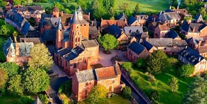 An aerial view of a historic village with traditional architecture, narrow streets, and a central church. - Hotel Le Relais de Castelnau (Loubressac)