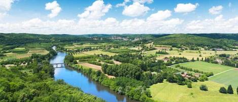 A river flowing through a valley with green fields and scattered houses.