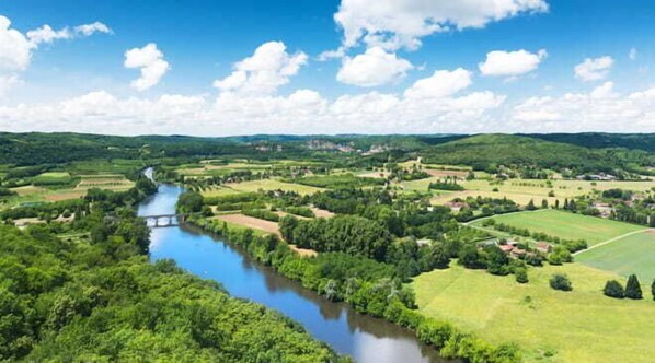 Un río serpentea por un valle con campos verdes y casas dispersas.