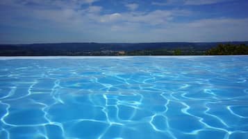 Een buitenzwembad, een infinity pool, ligstoelen bij het zwembad