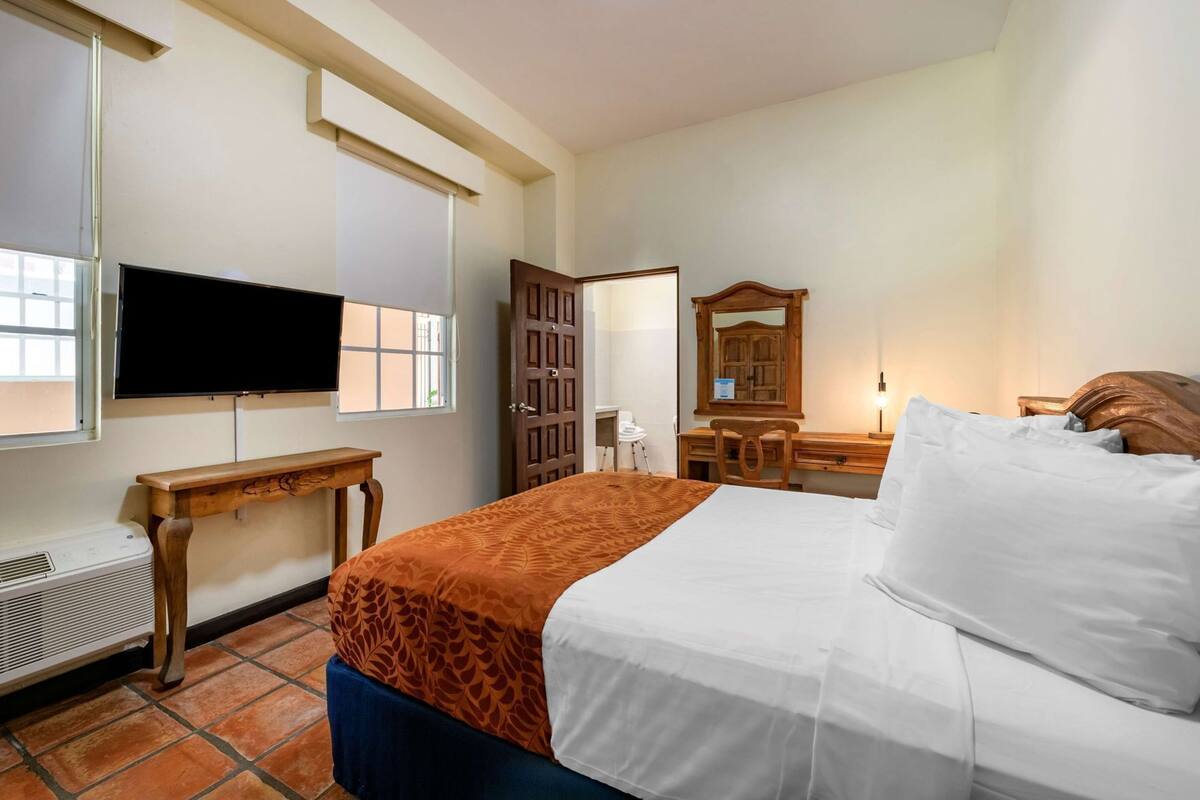 Ein Hotelzimmer mit Bett, Schreibtisch, Stuhl, Fernseher und Fenster.