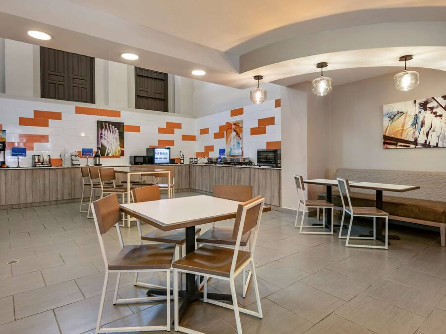 Een modern restaurant met een centrale balie, een zithoek en een muurschildering.