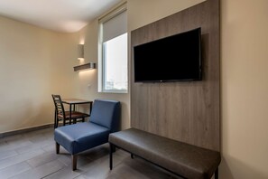 Una habitación moderna con una televisión de pantalla plana montada en una pared de madera, una pequeña mesa con una silla y un banco.