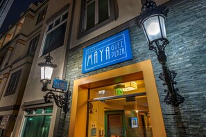 L’entrée d’un hôtel, avec une enseigne indiquant « Hôtel Maya Plaza » et une autre, placée au-dessus de la porte, indiquant « SORTIE ».
