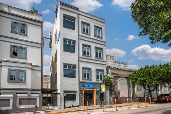 Un immeuble à plusieurs étages avec une enseigne bleue sur laquelle on peut lire « HÔTEL MAYA ».