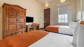 Une chambre d’hôtel avec deux lits, une armoire en bois, un bureau avec une chaise, une télévision et une fenêtre donnant sur un paysage agréable.