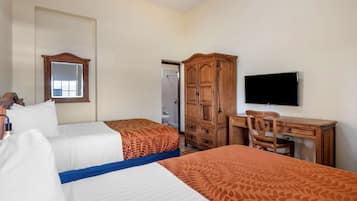 A hotel room with two beds, a wooden wardrobe, a desk with a chair, a television, and a mirror.