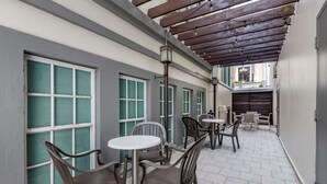 A covered outdoor seating area with tables and chairs, a pergola overhead, and a view of the street.