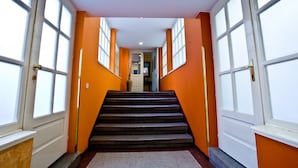 A hallway with a carpeted staircase leading to a door with a window. - Hotel Melantrich (Prague)