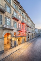 En historisk byggnad med en framträdande hotellskylt, välvda fönster och en kullerstensgata.
