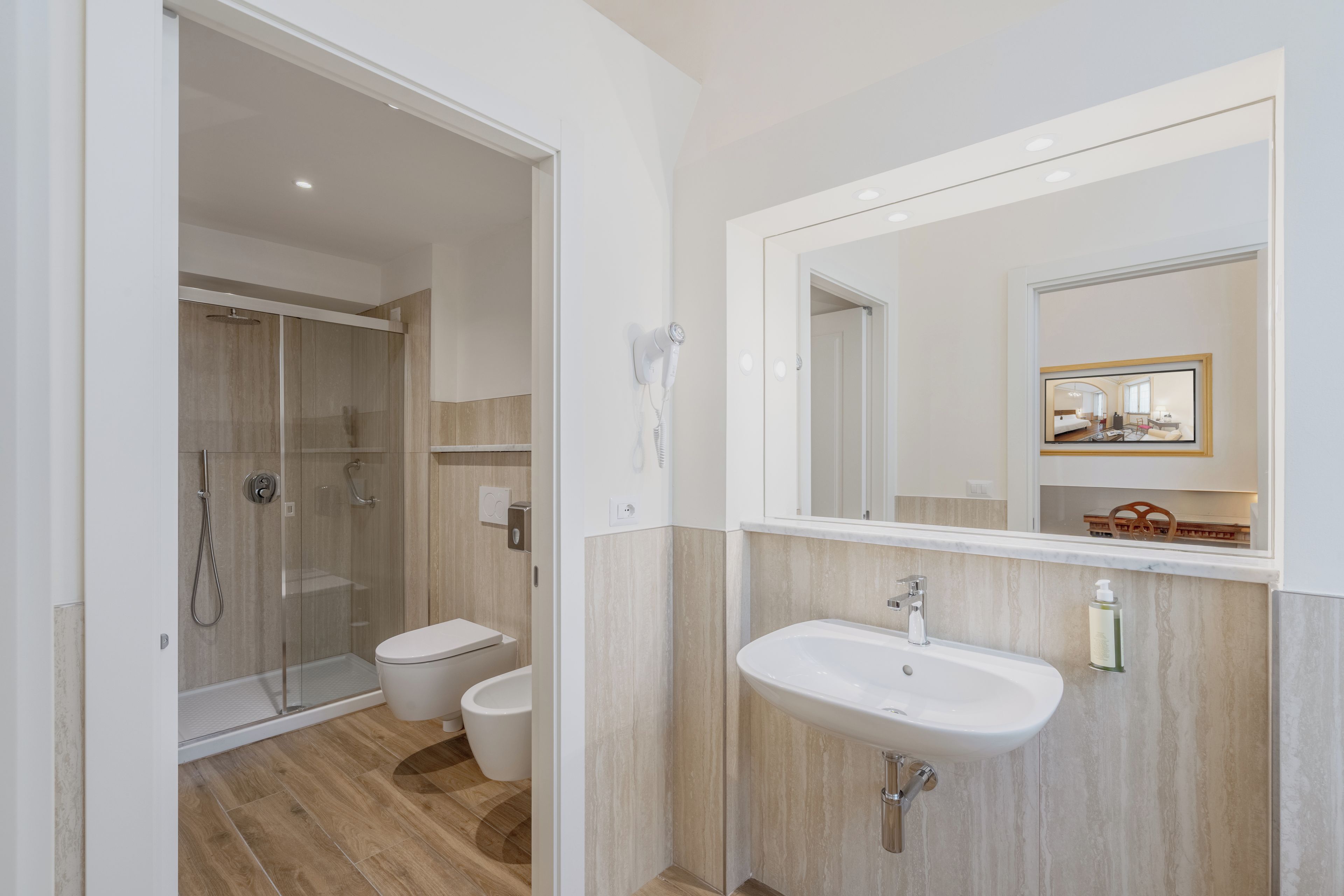 Un baño moderno con ducha de vidrio, inodoro y lavamanos con espejo.