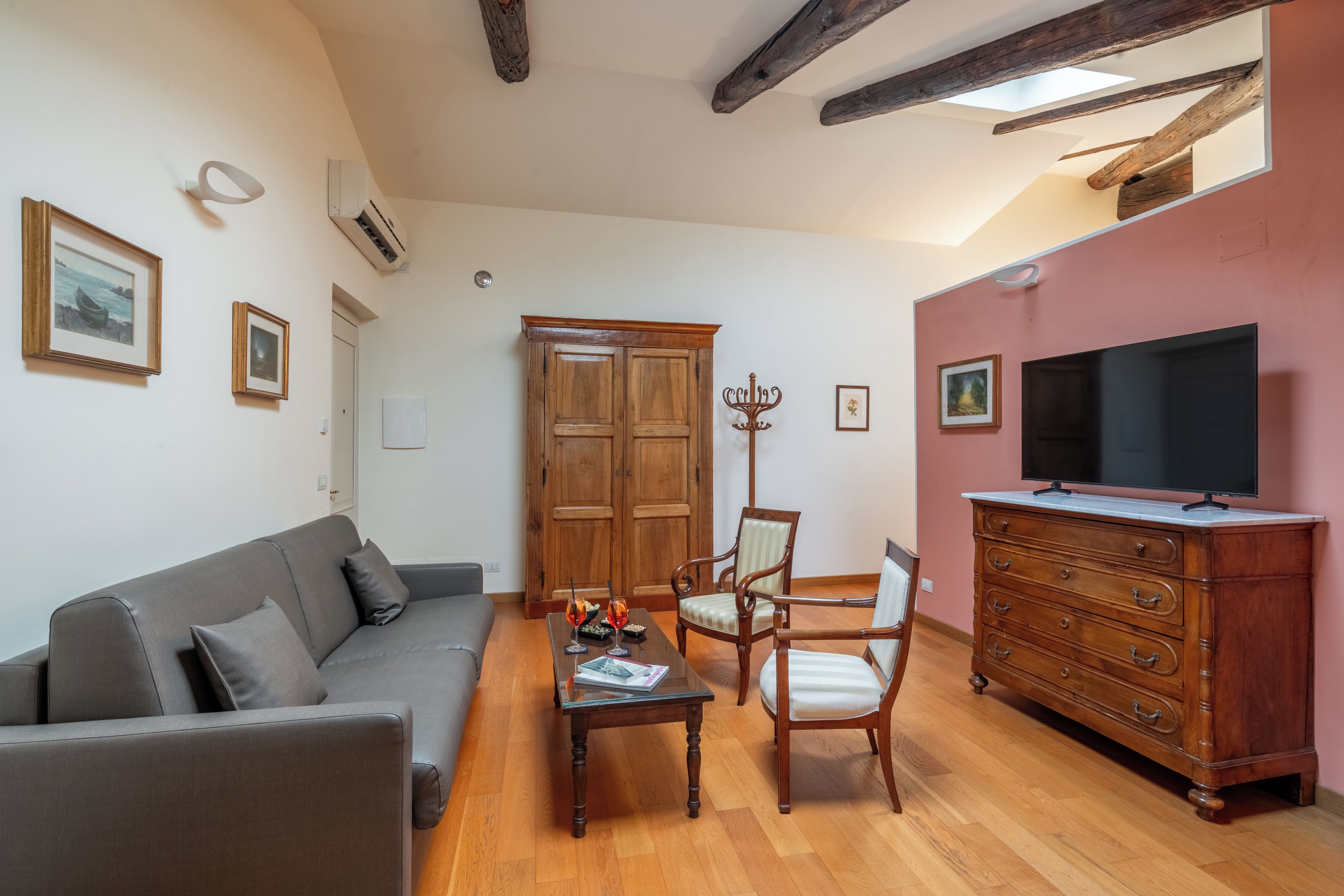 A living room with a sofa, chairs, a coffee table, a TV, and a wooden cabinet.