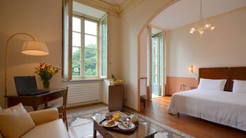 Una habitación de hotel con cama, escritorio con ordenador portátil, mesa de desayuno y ventanas amplias.