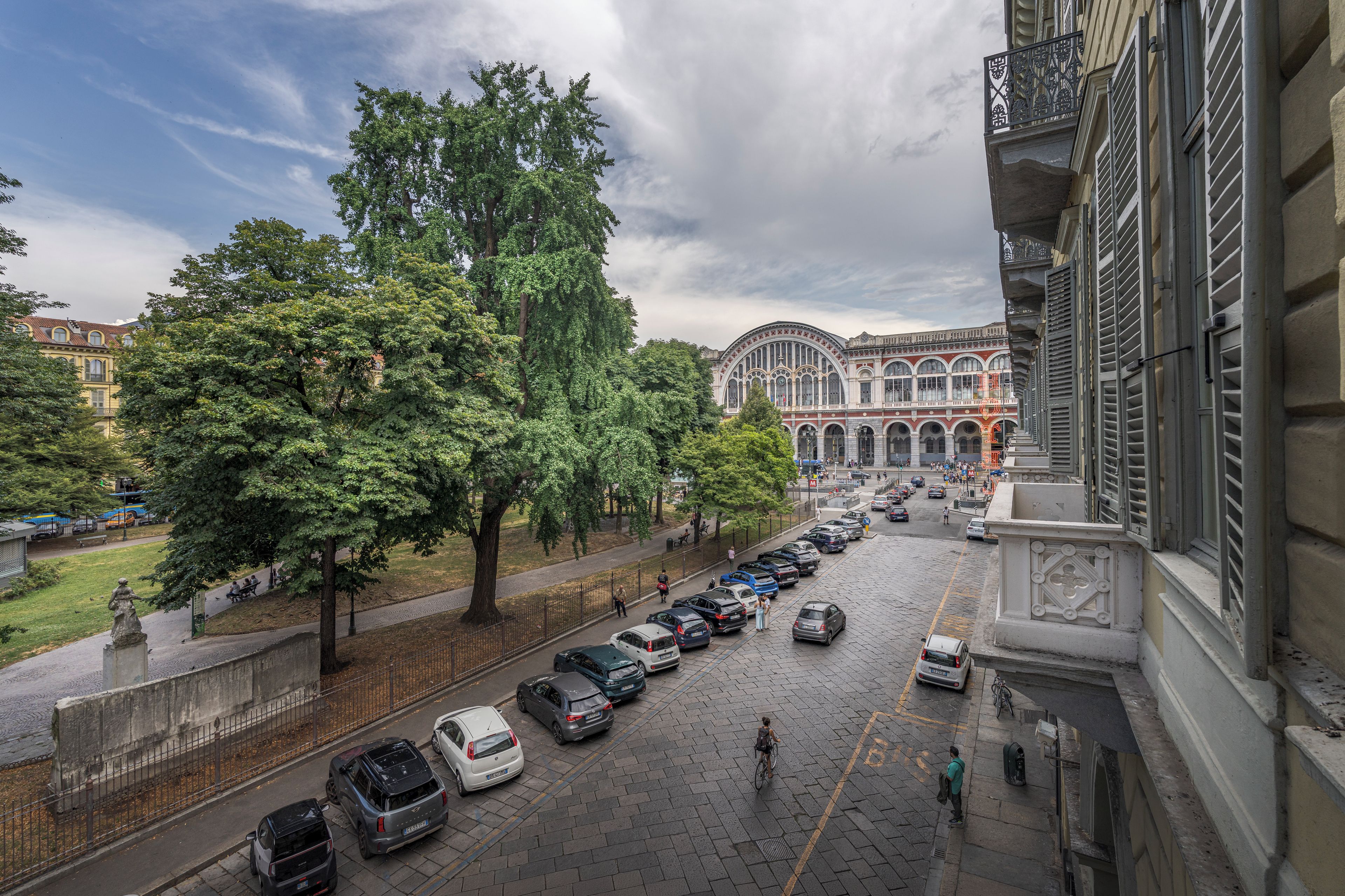 Una vista di strada con auto parcheggiate, un marciapiede e un edificio dall'architettura classica.