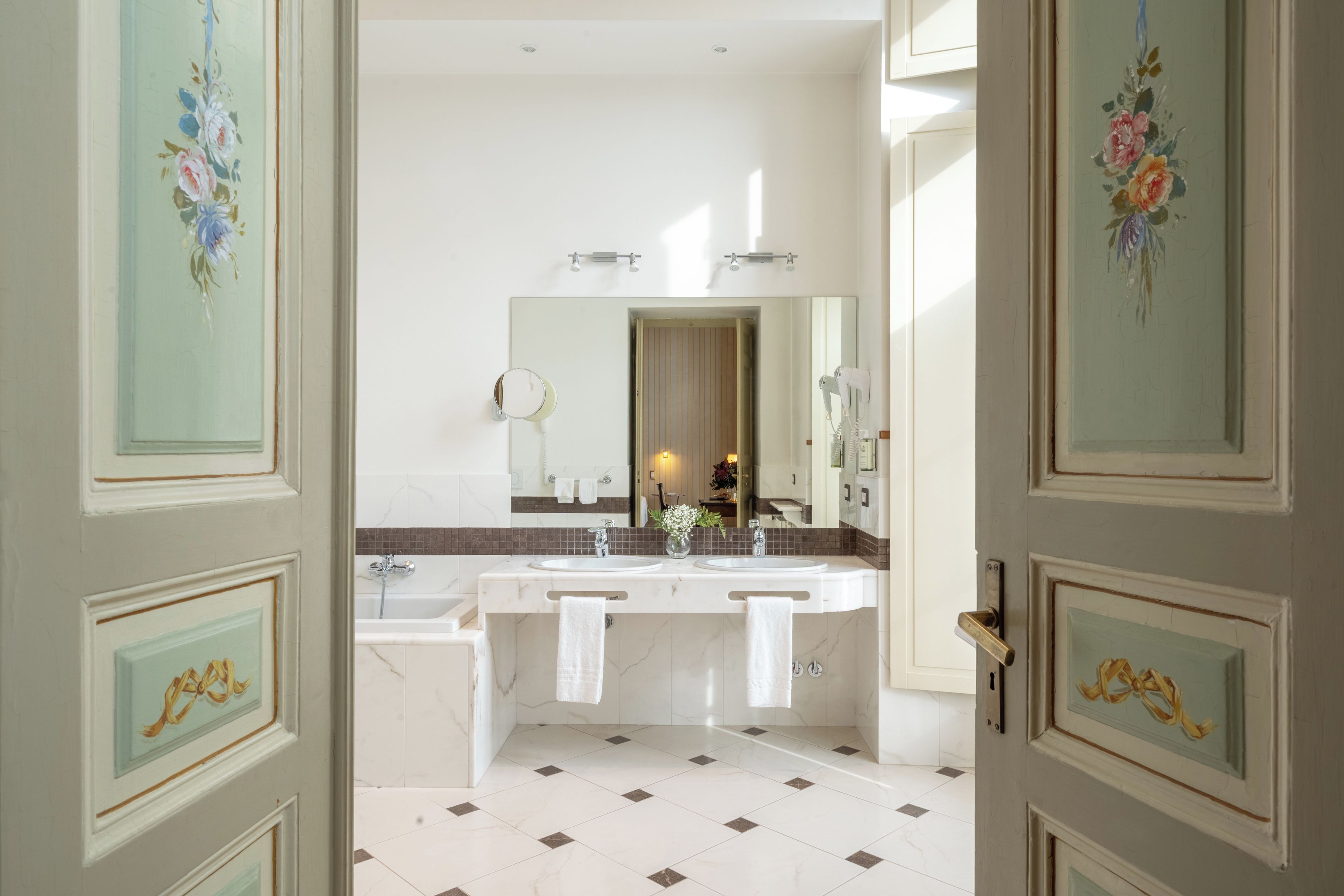 Ein Badezimmer mit einem Doppelwaschbecken, einer Badewanne und einem großen Spiegel.