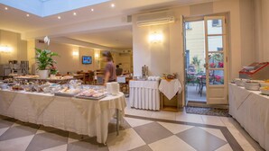 Ein Hotel-Speisesaal mit einem Buffet, einer großen Pflanze in einem Topf und einem Fernsehbildschirm im Hintergrund.