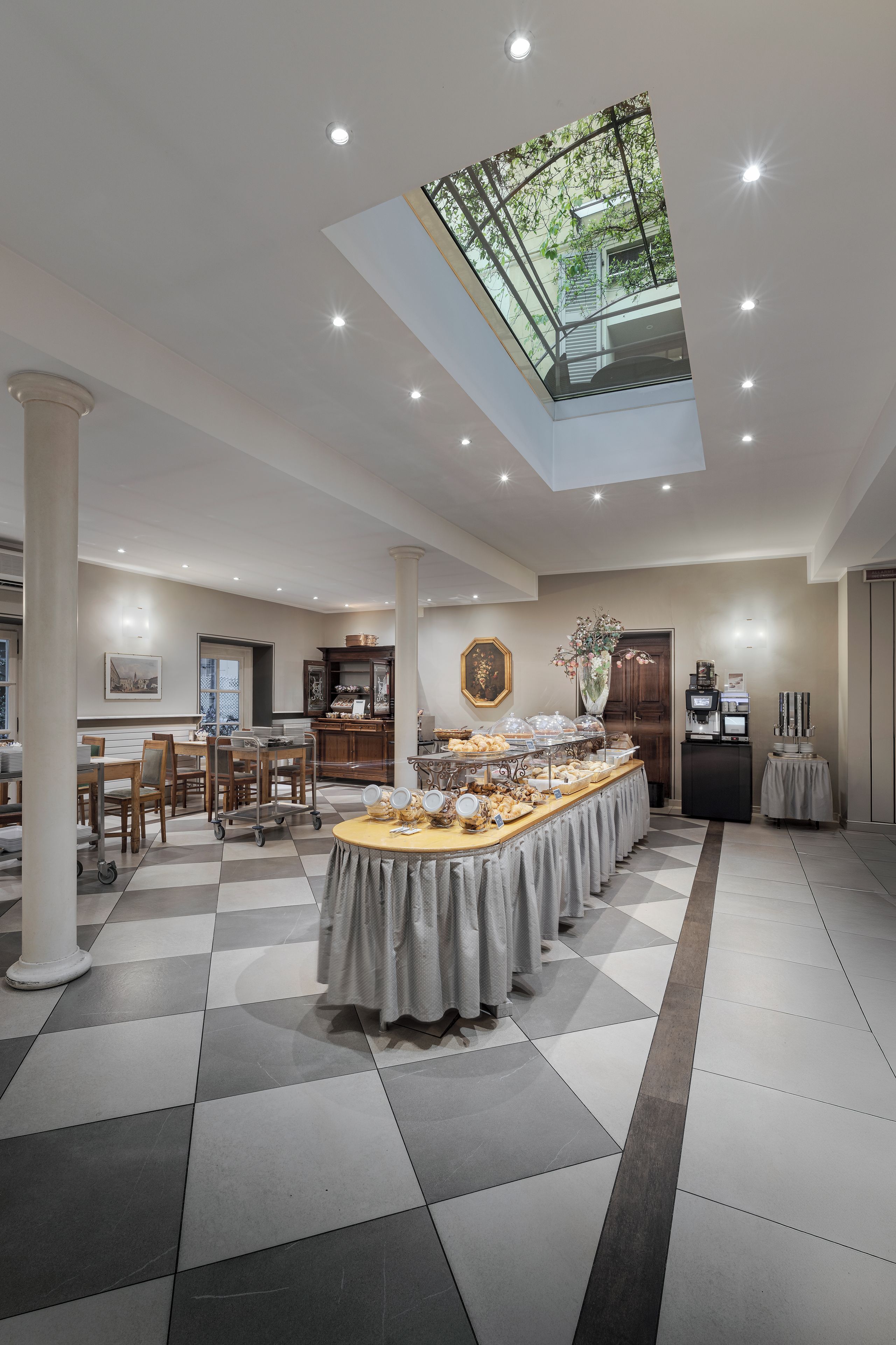 A spacious room with a high ceiling, a skylight, and a buffet table with various food items.
