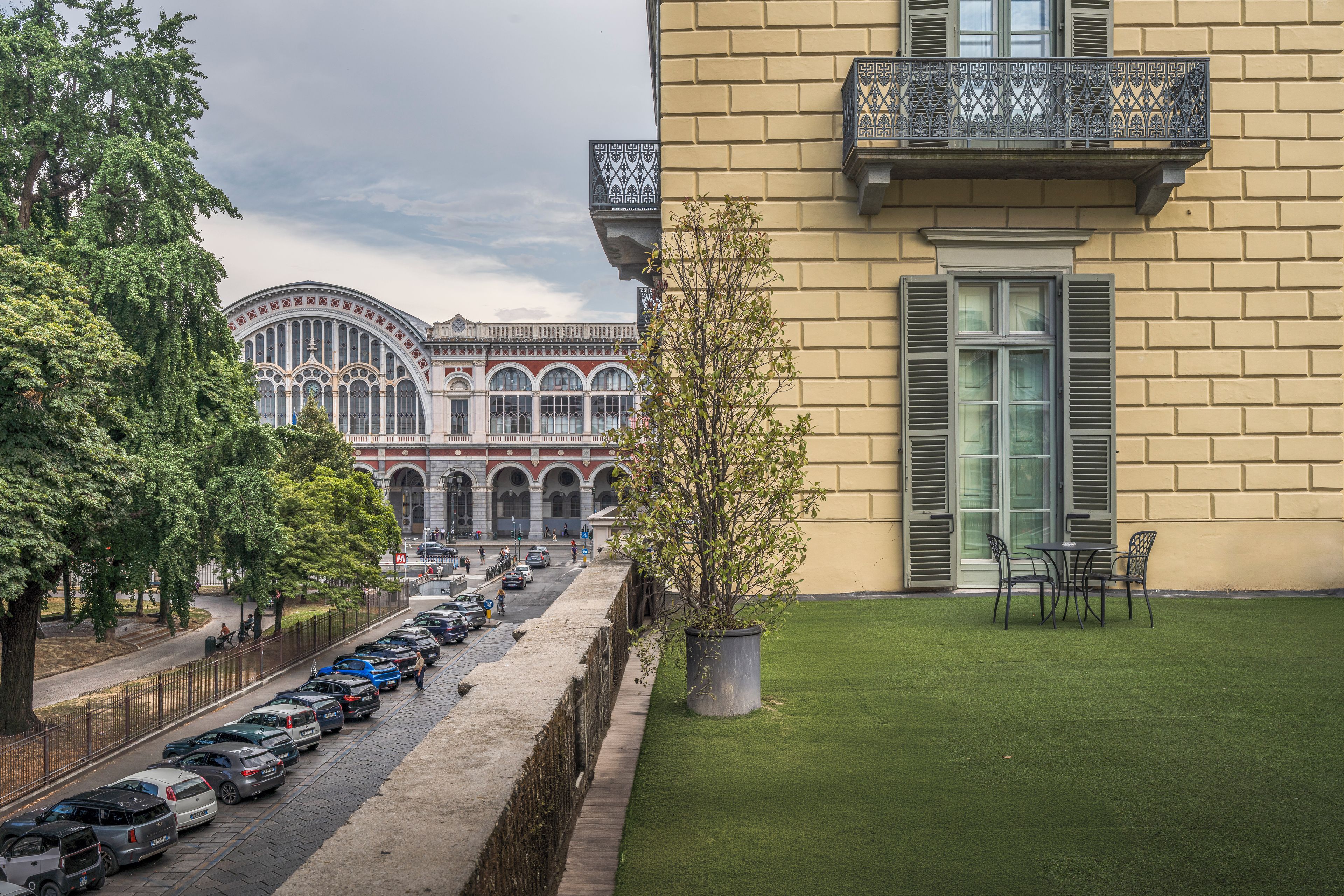 A building with a balcony, a parking lot, and a tree.