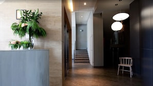 A hallway with a reception desk, a staircase, and a seating area. - Hotel Rice Bulevar (Burgos)