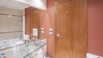 Un baño con un lavabo de vidrio, ducha y puertas de madera.