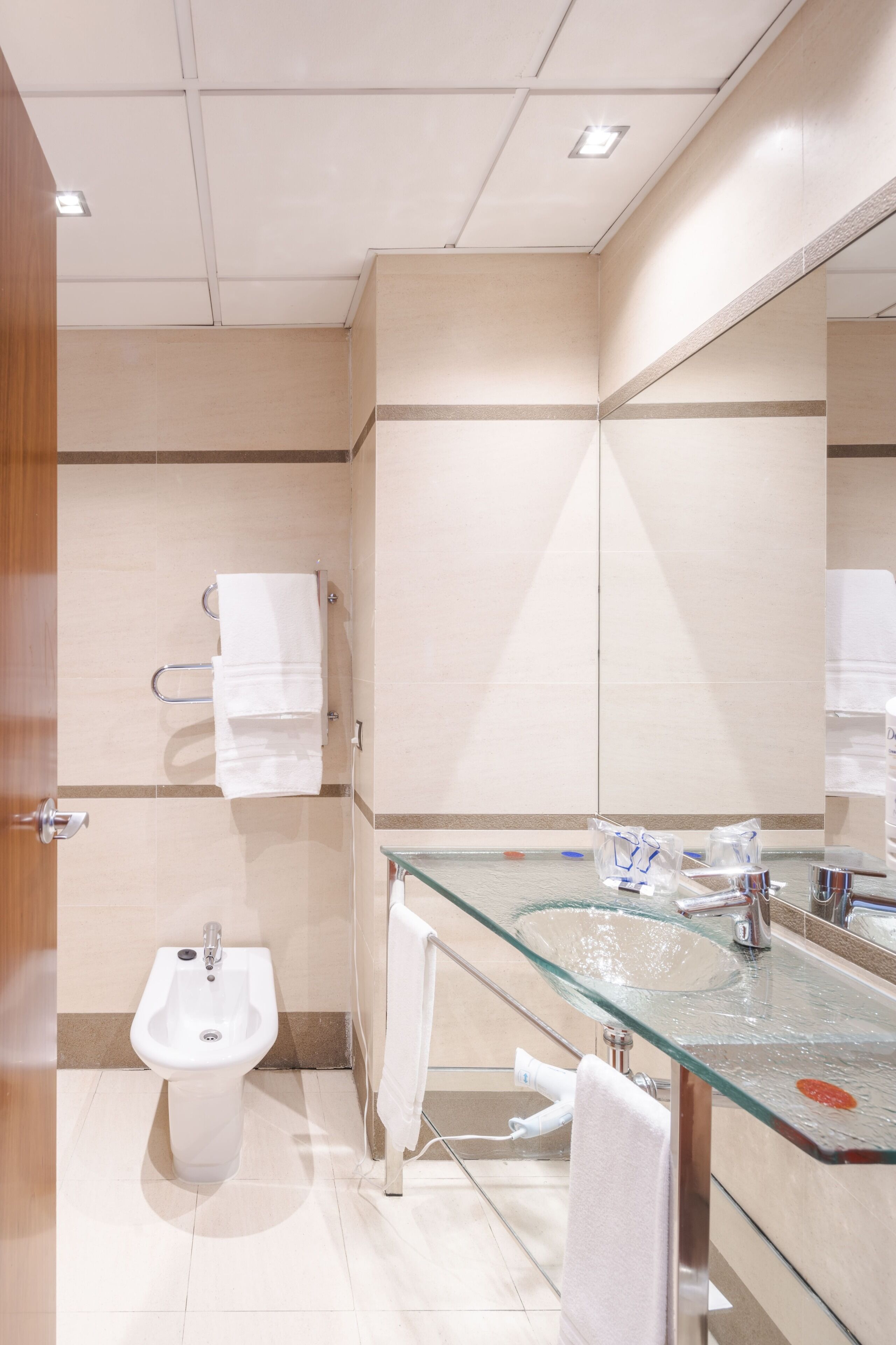 Une salle de bain moderne avec un lavabo en verre, un bidet et un miroir.