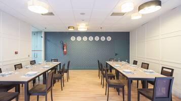 Un salón de conferencias con mesas largas, sillas y una pared azul estampada.