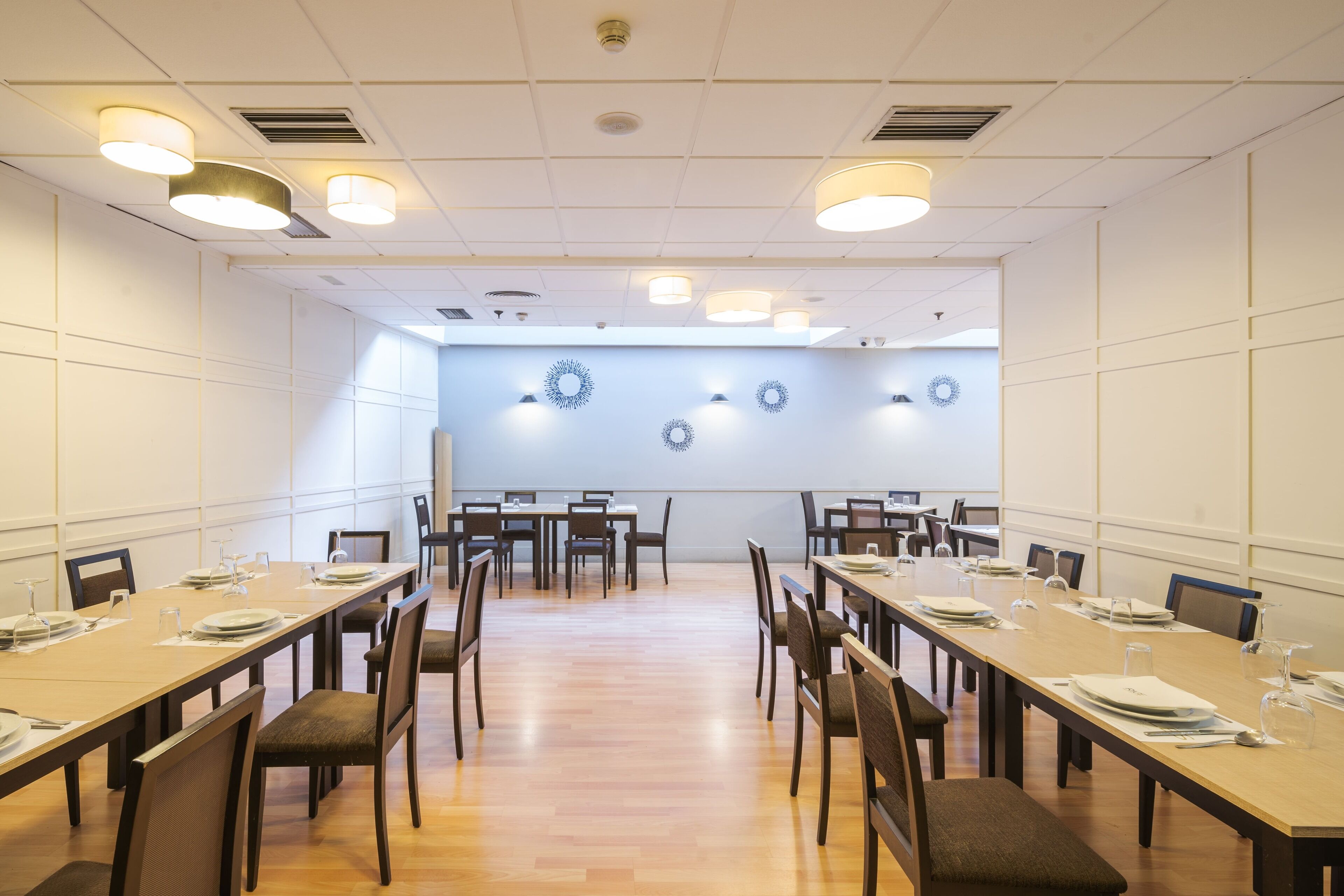 A conference room with long tables, chairs, and ceiling lights.