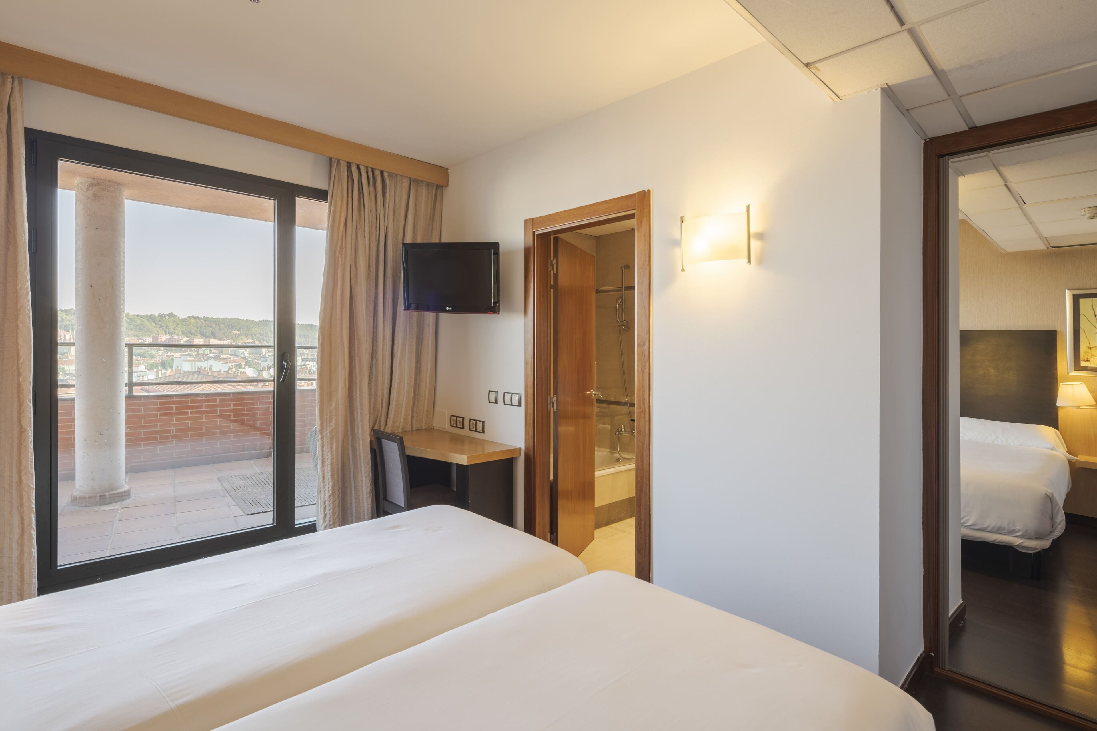 Une chambre d’hôtel équipée d’un lit, d’un bureau, d’une télévision et d’une salle de bain avec douche.