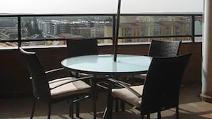 A round table with chairs and a large umbrella on a balcony with a city view. - Hotel Rice Bulevar (Burgos)