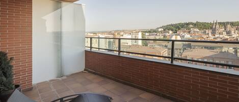 A balcony with a view of a cityscape, including a prominent cathedral.