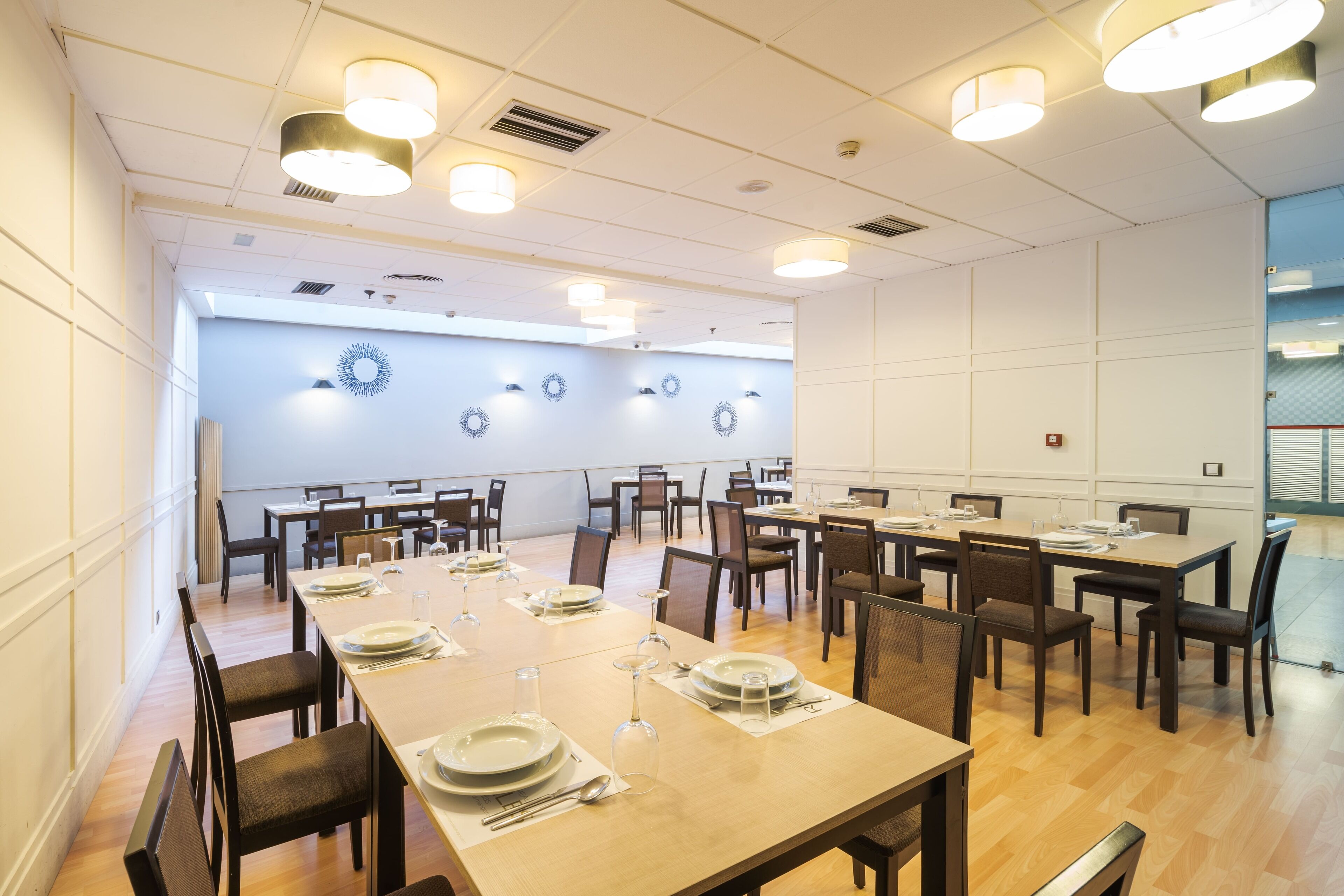 A conference room with multiple tables set for dining, equipped with chairs and plates.