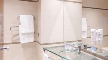 Un baño moderno con un lavabo de vidrio, un bidé y un espejo grande.