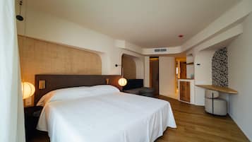 Una habitación de hotel moderna con una cama grande, un escritorio y una zona de estar.