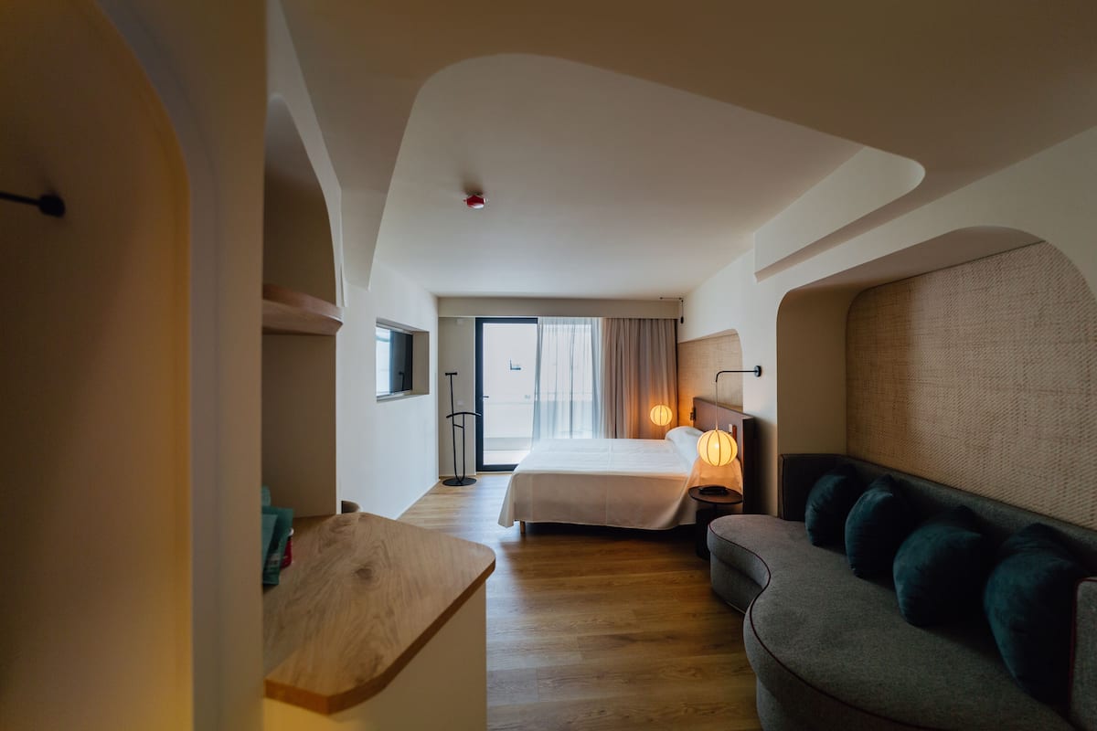 Habitación de hotel con cama, sofá, escritorio y vistas al exterior.