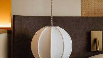 Une chambre d’hôtel moderne avec un lit rond, une table de chevet ronde et une lampe suspendue.