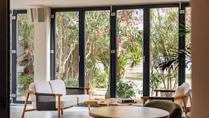 Una habitación moderna con ventanas amplias, una mesa redonda de madera y dos sillas.