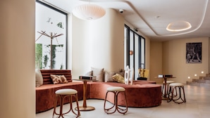 Una sala de estar moderna con un sofá curvo, taburetes de madera y un ventanal con vistas a zonas verdes.