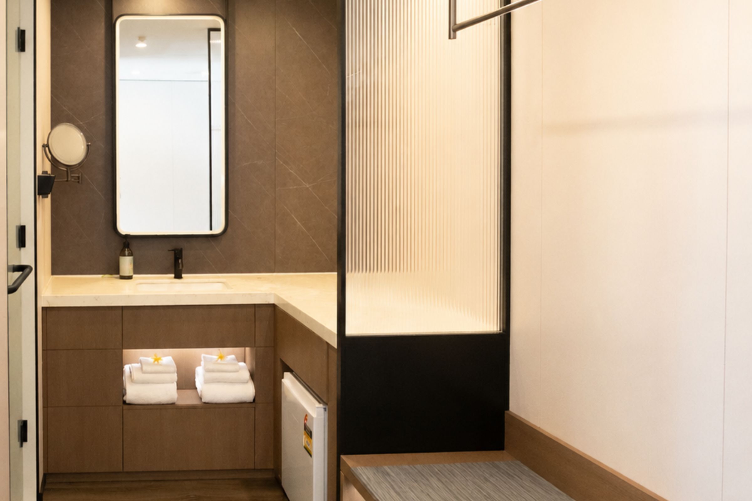 A modern bathroom with a sink, mirror, towel rack, and a shower area.