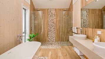 A modern bathroom with a wooden floor, two sinks, a large mirror, and a shower area.