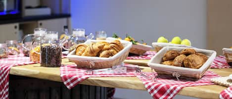 Un bufé de desayuno con diversas opciones de pastelería, frutas y bebidas.