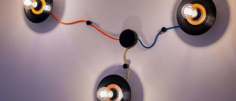 A wall-mounted lighting fixture with three vinyl records as light sources, connected by wires.