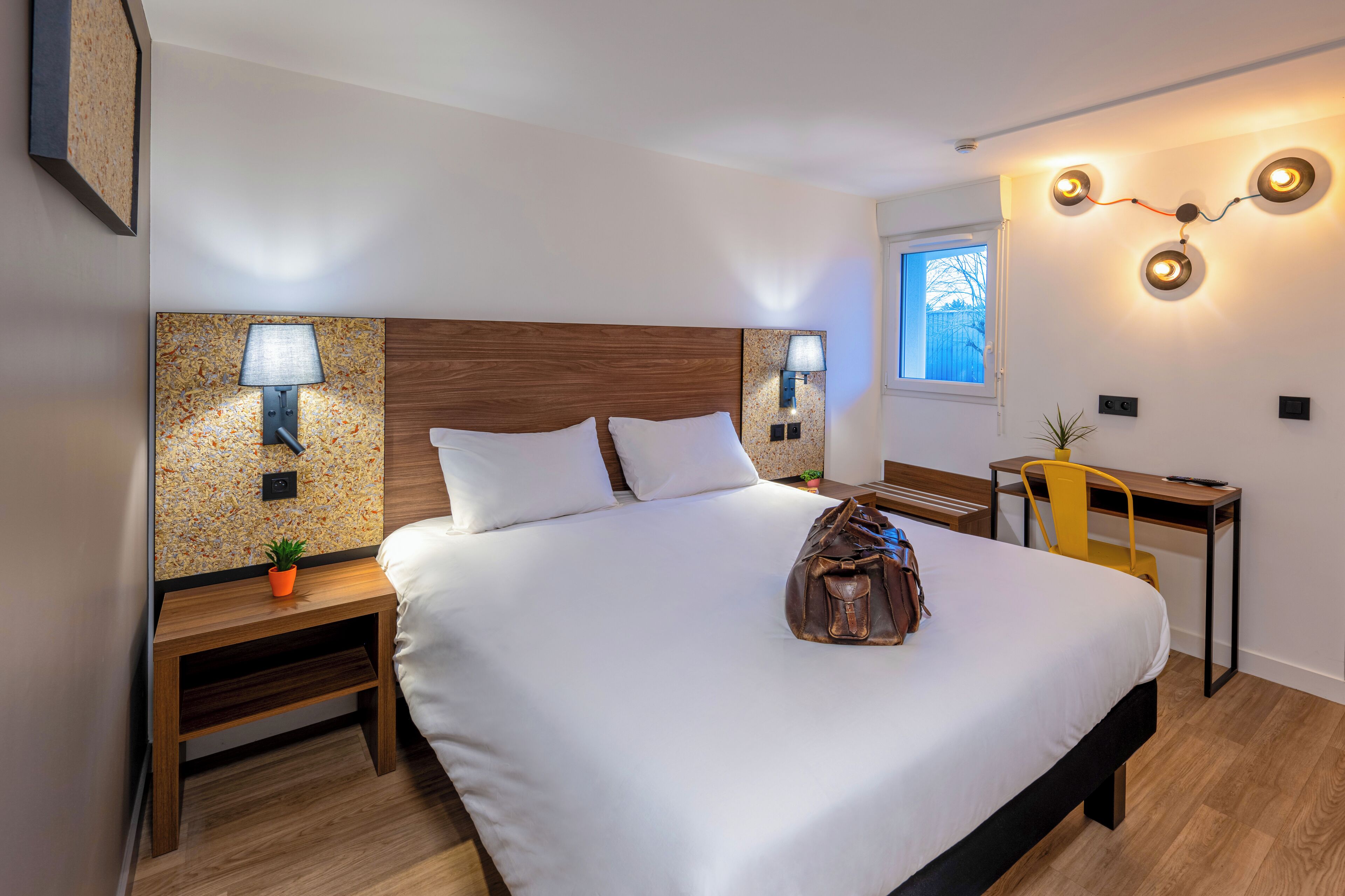 Une chambre d’hôtel avec un grand lit, deux tables de chevet, un bureau et une chaise.