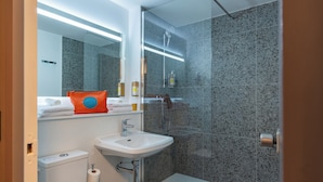 Une salle de bain moderne avec une douche à parois de verre, un lavabo blanc et des toilettes.