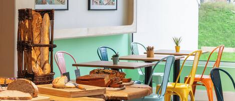 A dining area with a rustic wooden table, colorful chairs, and a wicker bread basket.