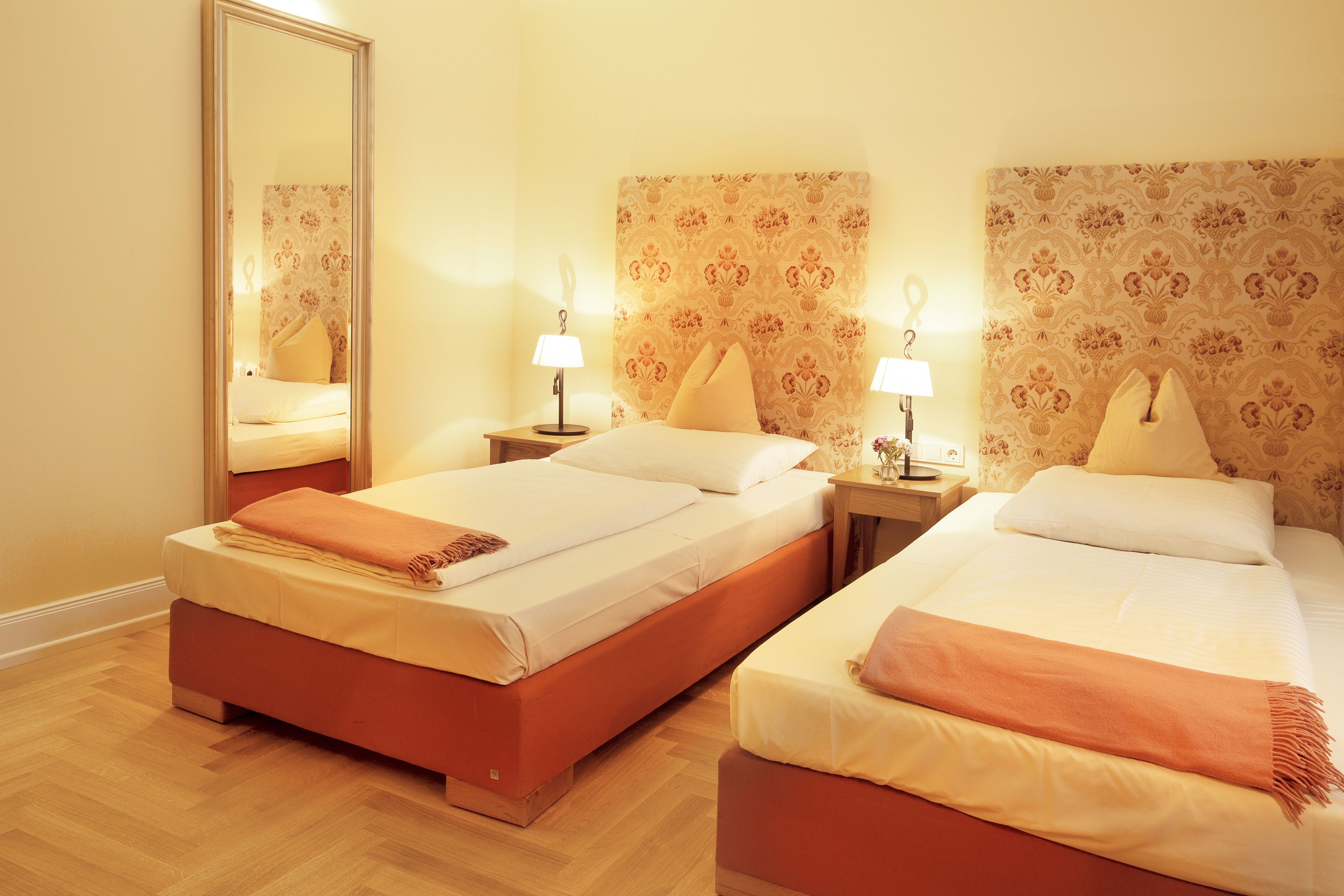 Une chambre d’hôtel avec deux lits, un grand miroir et deux lampes de chevet.