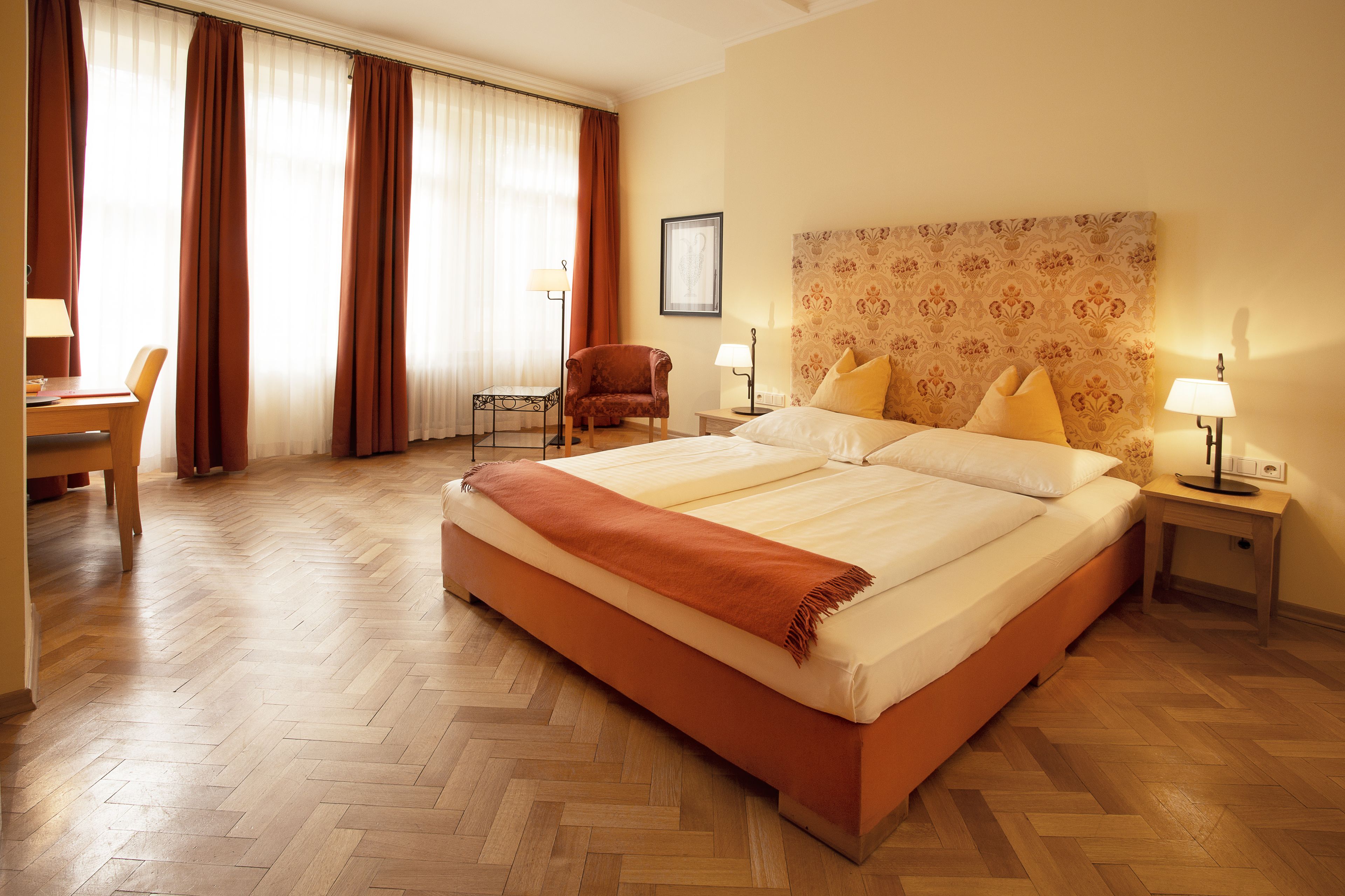 Une chambre d’hôtel avec un grand lit, un bureau, une chaise et une fenêtre avec des rideaux.