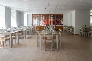 A spacious dining area with multiple tables and chairs, large windows, and a view of the outside. - Waldhotel Eiche (Lübbenau/Spreewald)