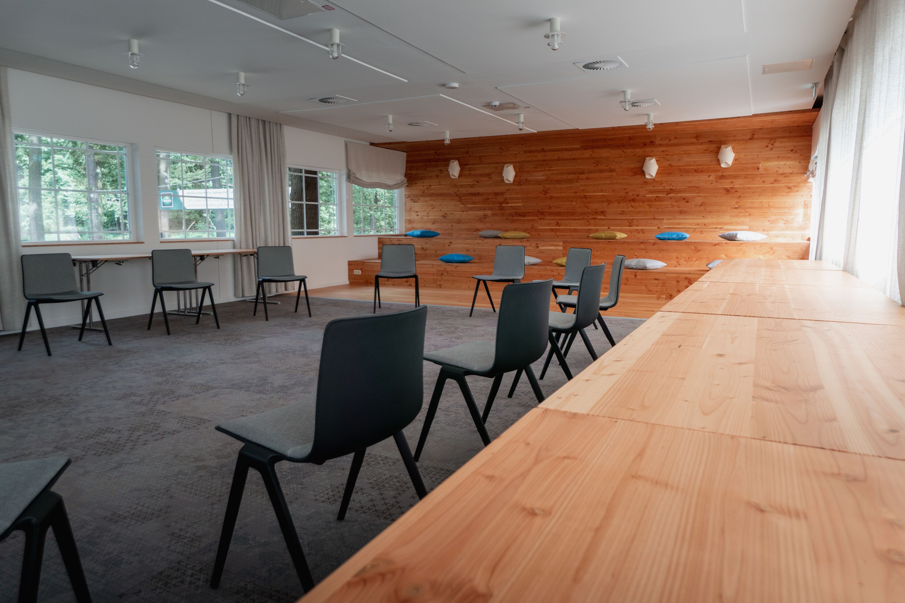 Un salón de conferencias con una larga mesa de madera, varias sillas y una pared de madera con detalles decorativos.