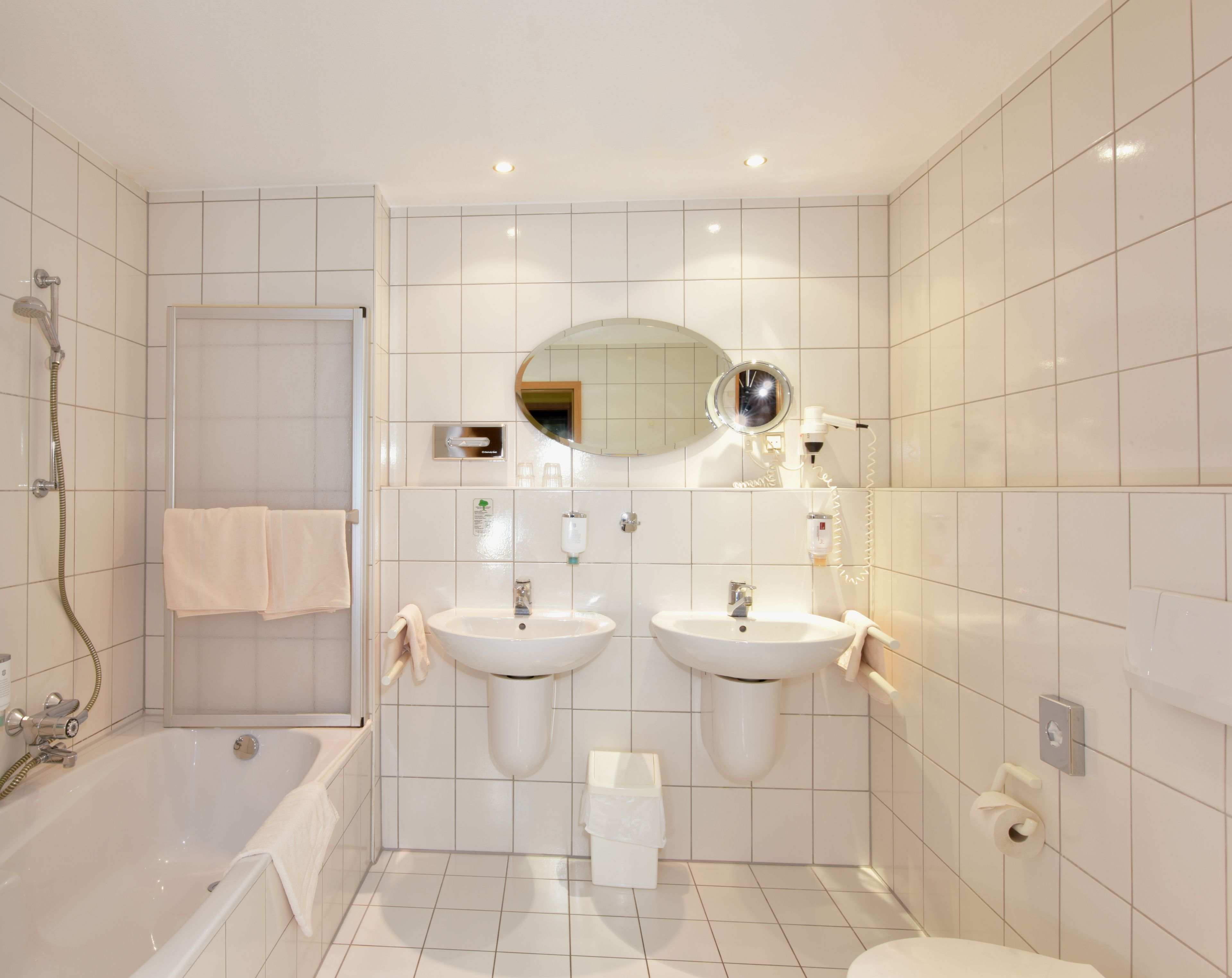 A modern bathroom with two sinks, a bathtub, a shower, and a mirror.